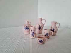 a group of pink and blue vases sitting on top of a white table cloth