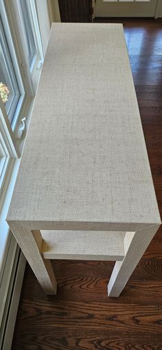 a white table sitting on top of a hard wood floor next to a door and window