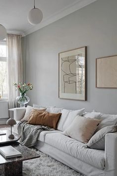 a living room filled with white furniture and lots of pillows on top of it's couch