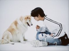 a boy sitting next to a dog on the ground with it's mouth open