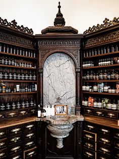 an old fashioned pharmacy cabinet with many bottles on the shelves and a sink in it