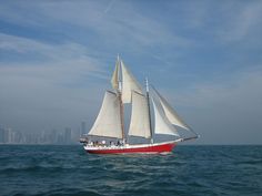 a red and white sail boat in the ocean