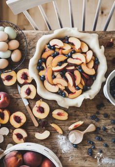 fresh peaches, blueberries and eggs in bowls on a wooden table with utensils