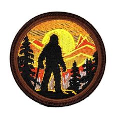 a bigfoot is silhouetted against the setting sun in this embroidered iron - on patch