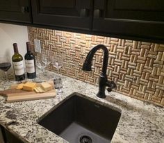 a kitchen sink with wine bottles and cheese on the counter top next to it,