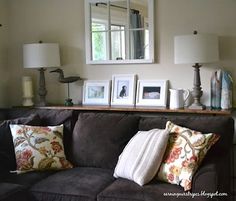 a living room filled with lots of furniture and pictures on top of a shelf above the couch