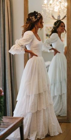 a woman in a white dress looking at herself in the mirror