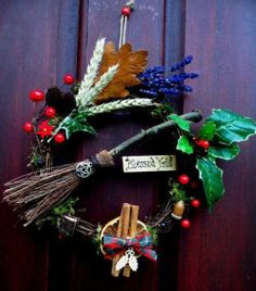 a wreath is hanging on the door with some leaves and other things around it that say merry christmas