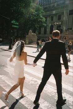 a bride and groom walking across the street