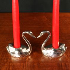 two candles are placed next to each other on a table with one candle in the shape of a swan