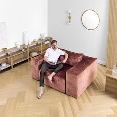 a man sitting on top of a brown couch in a living room