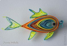 a fish made out of colored paper sitting on top of a white surface