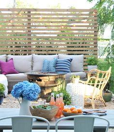 an outdoor patio with chairs, table and flowers on the table in front of it