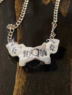 a dog bone necklace is shown on a wooden surface, with the word bones written in black ink