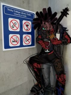 a man with dreadlocks sitting next to a sign