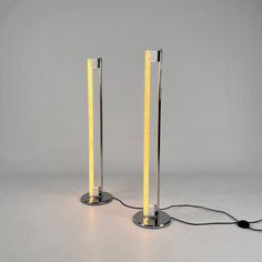 two floor lamps that have been turned on to look like they are standing next to each other