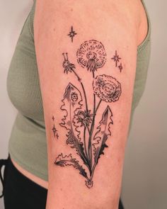 a woman's arm with a dandelion tattoo design on the left shoulder