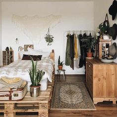 a bed room with a neatly made bed next to a dresser and potted plant