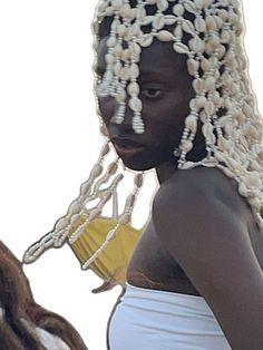 a woman with braids and pearls on her head is standing next to a horse