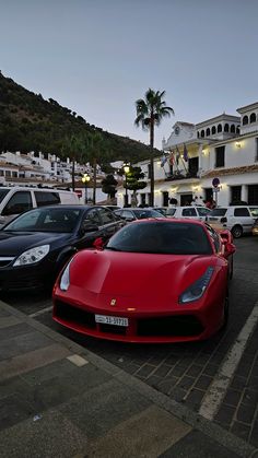 a red sports car parked in front of a white building on the side of a road