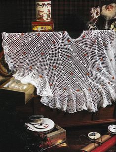 there is a white crocheted table cloth on top of a wooden box with other items around it