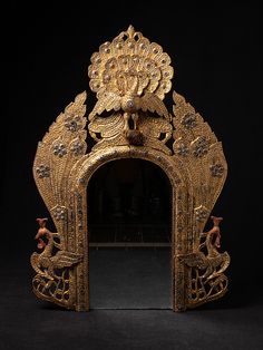 an ornately decorated gold mirror against a black background