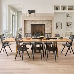 a dining table with six chairs around it in front of a fireplace and bookshelves