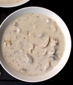 two bowls filled with soup on top of a black table next to silver spoons