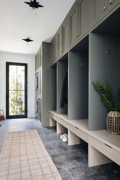 a hallway with gray walls and wooden cabinets, an area rug on the floor and a door leading to another room