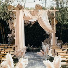 an outdoor wedding ceremony with white draping and pamolite flowers on the aisle