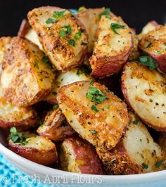 potatoes with herbs and seasoning in a white bowl on a blue tablecloth, ready to be eaten