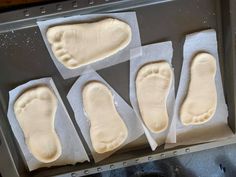 four pairs of foot prints on waxed paper in a baking pan, with one being cut into smaller pieces