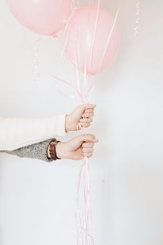 a woman holding pink balloons in her hand