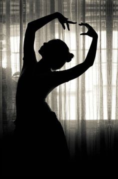 the silhouette of a woman standing in front of curtains