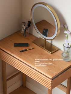 a wooden desk with a mirror, pen and flowers in a vase on top of it