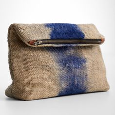 a blue and beige clutch bag on a white surface with a zippered closure that is open