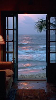 an open door leading to the ocean at dusk with a palm tree in the foreground