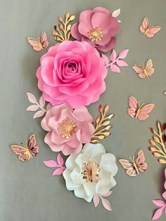 pink and white paper flowers with butterflies on the wall behind them, in front of a gray background