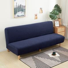 a blue couch sitting on top of a hard wood floor next to a white wall