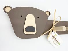 a brown bear head hanging from the side of a wooden wall decoration with a tag attached to it