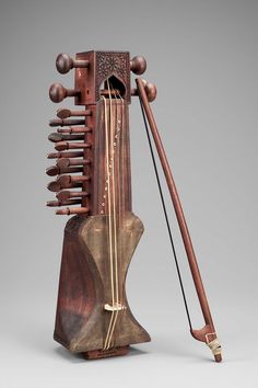 an old musical instrument with many strings attached to it's body and wooden stand