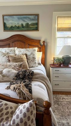 a bed sitting in a bedroom next to a dresser and window with pictures on the wall