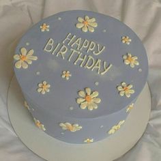 a blue birthday cake with white flowers and the words happy birthday on it's side