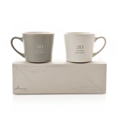 two grey coffee mugs sitting on top of a box with the words mr and mrs