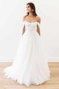 a woman in a white wedding dress standing on a wooden floor with her back to the camera