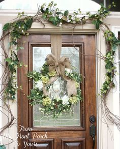 a wreath is hung on the front door with burlocks and greenery around it