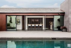 a house with a pool in front of it and some chairs on the outside side