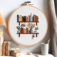 a cross stitch book shelf with books and vases