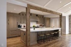 a large kitchen with an island in the middle and bar stools at the end