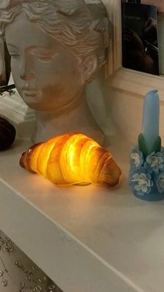 a croissant sitting on top of a table next to a candle and statue